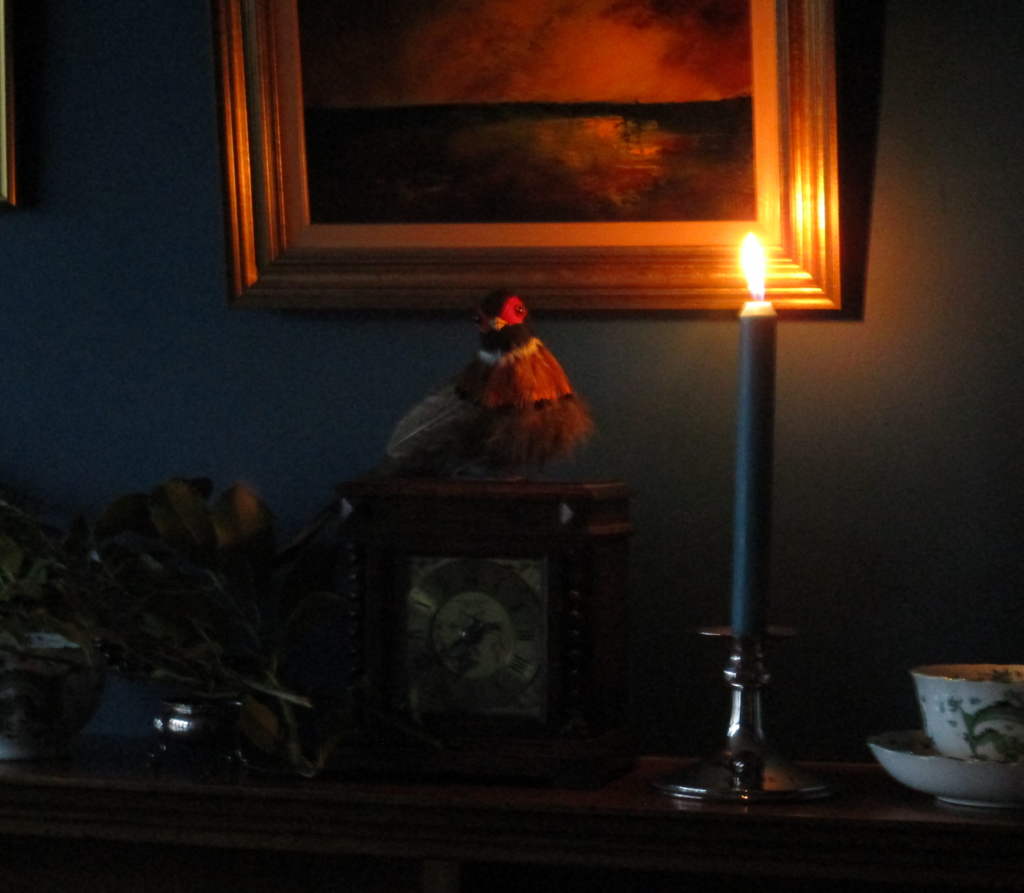 Photograph of a candlelit mantelpiece with an old clock and a model pheasant